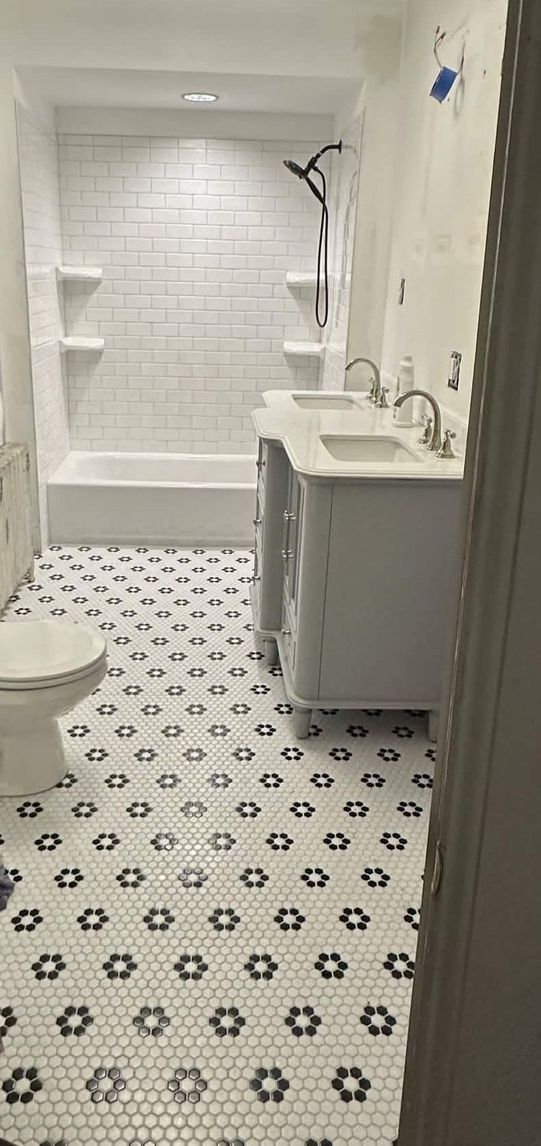 Finished bathroom remodel with a new tub surround, vanity and hex tile floor.