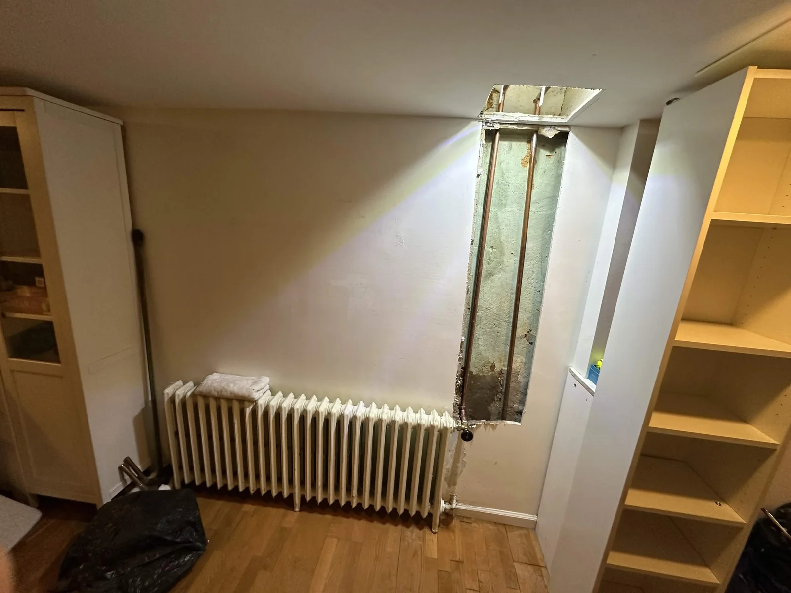 Copper piping reached through a wall opening during a leak repair.