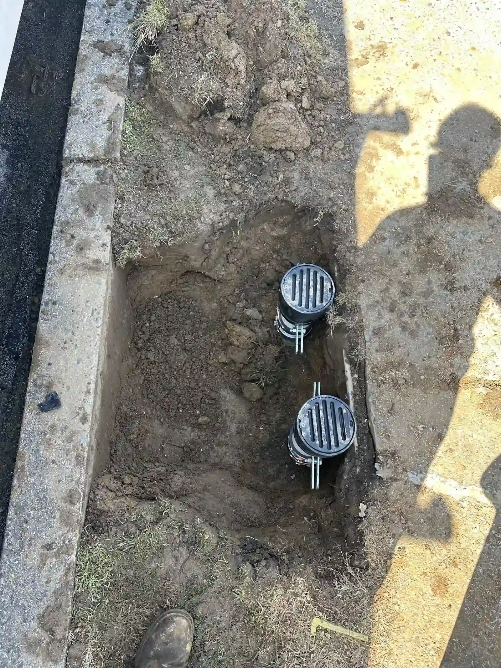 Drain access fittings exposed during an outdoor plumbing job.