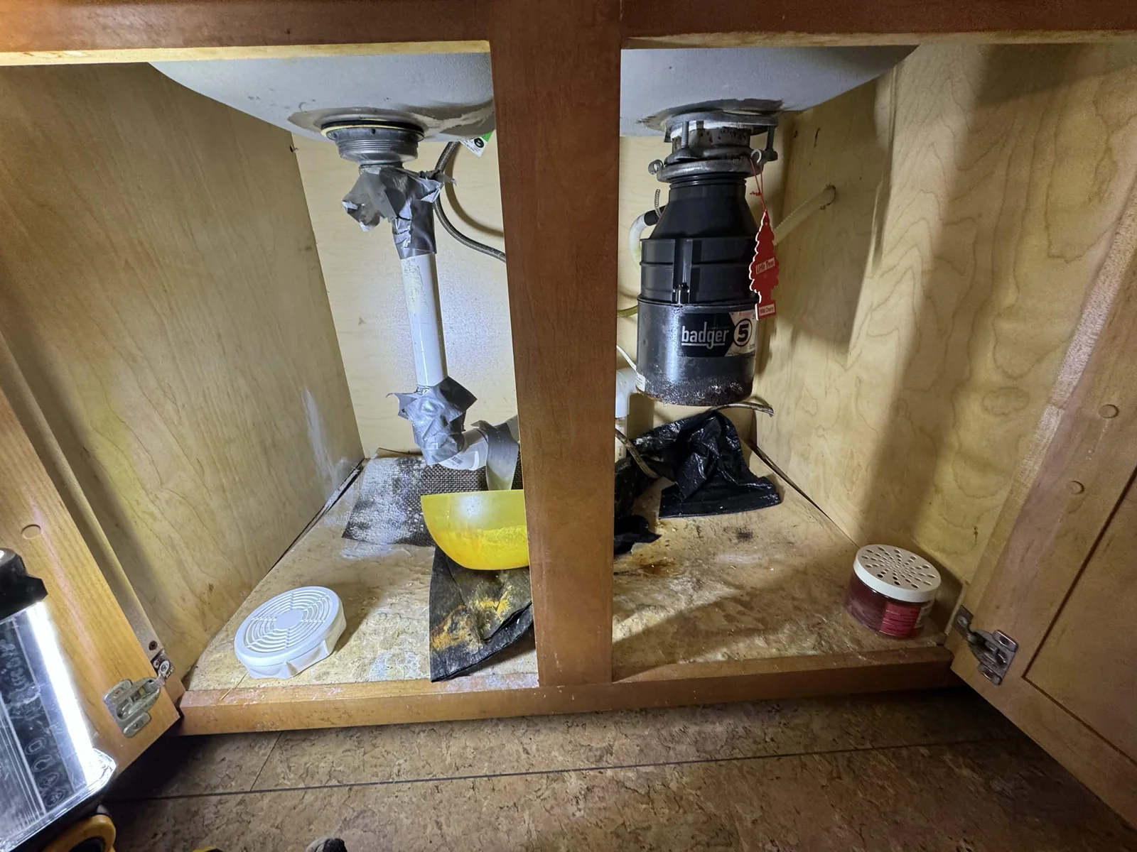 Before: taped drain connections and a damaged sink cabinet base.